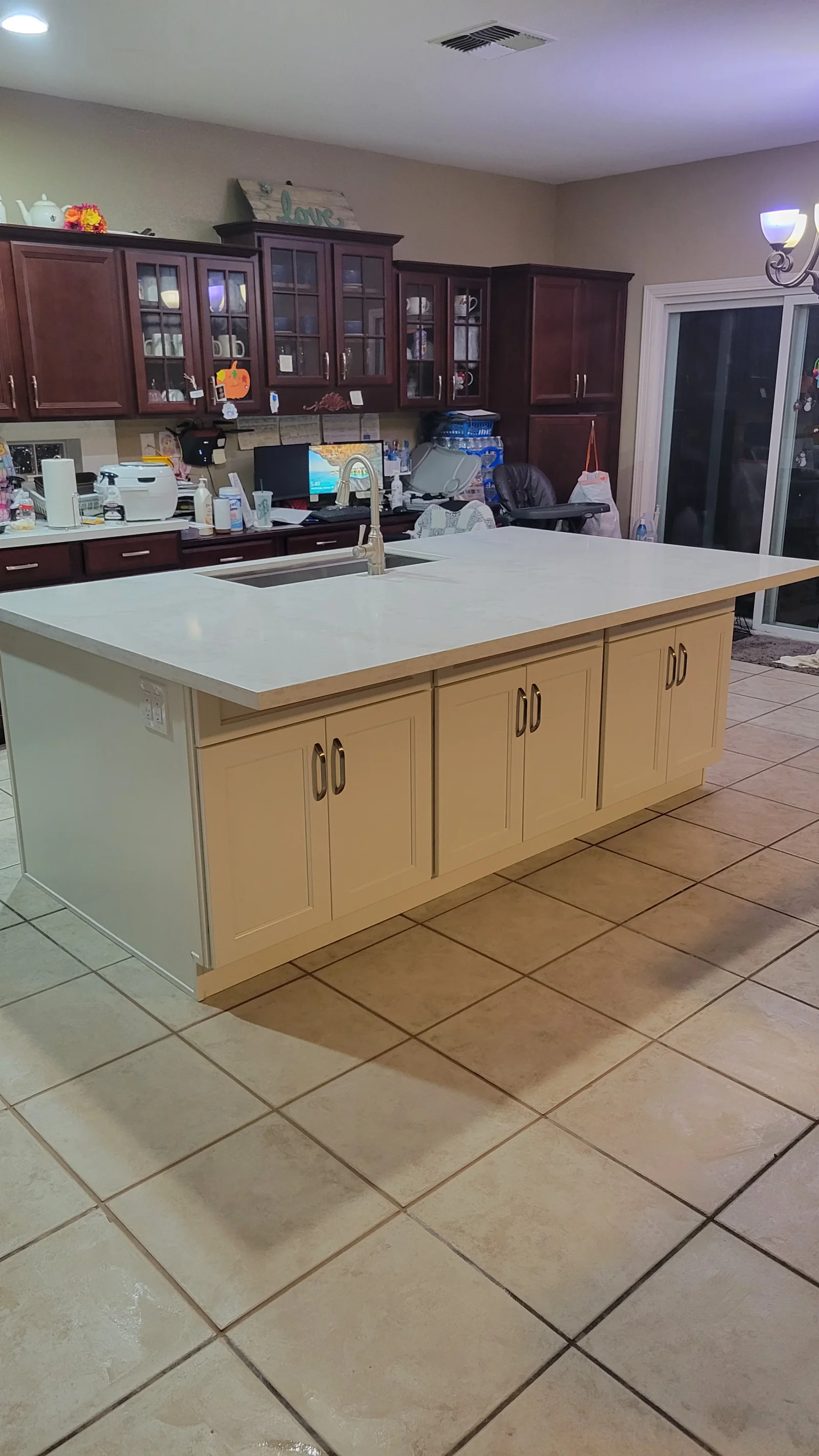 Kitchen island with cream shaker cabinets, white marbled quartz countertop, undermount stainless sink, and brushed nickel faucet